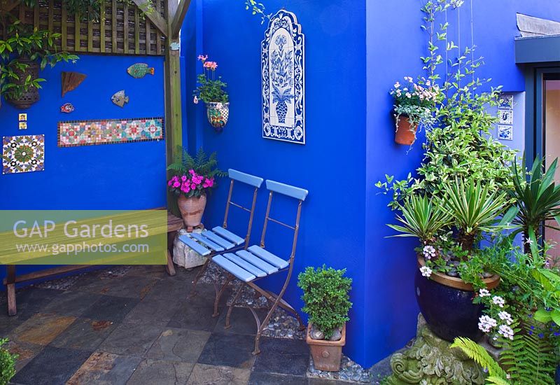 Small town garden - Courtyard with cobalt blue walls, blue cafe chairs and slate tiled floor. 
