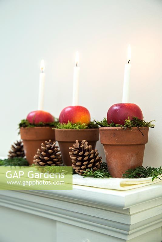 Christmas candle decorations made using terracotta pots, apples and moss