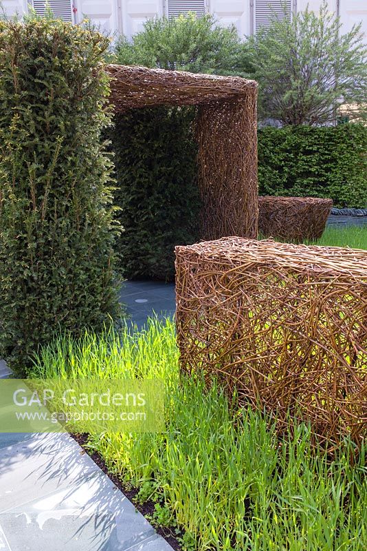 Stockton Drilling as Nature Intended Garden, Silver gilt medal winner, Chelsea Flower Show 2013. Woven willow sculptures flint path and yew hedging. 