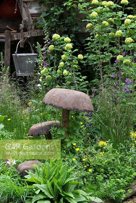 Wooden toadstools, treehouse, Digitalis,  Antirrhinum - Snapdragon, Cowslips and Buttercups in The NSPCC Garden of Magical Childhood