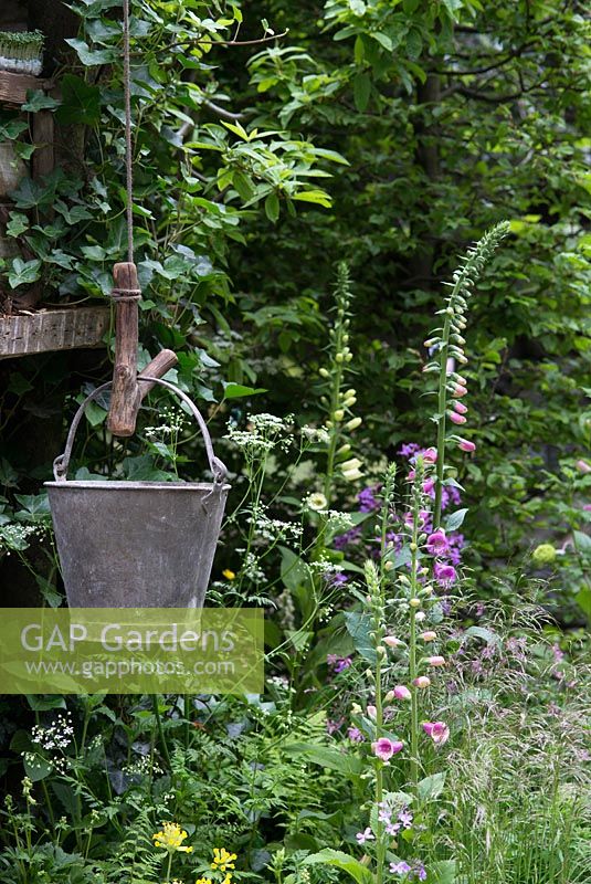 The NSPCC Garden of Magical Childhood, treehouse, galvanised bucket, Digitalis - Foxgloves, Hedera and Primula veris - Cowslips