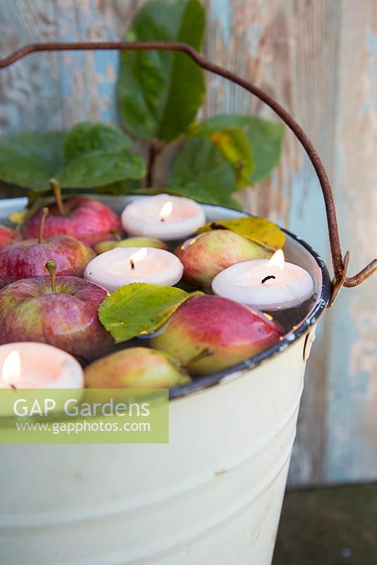 Floating candle display with apples in a bucket of water