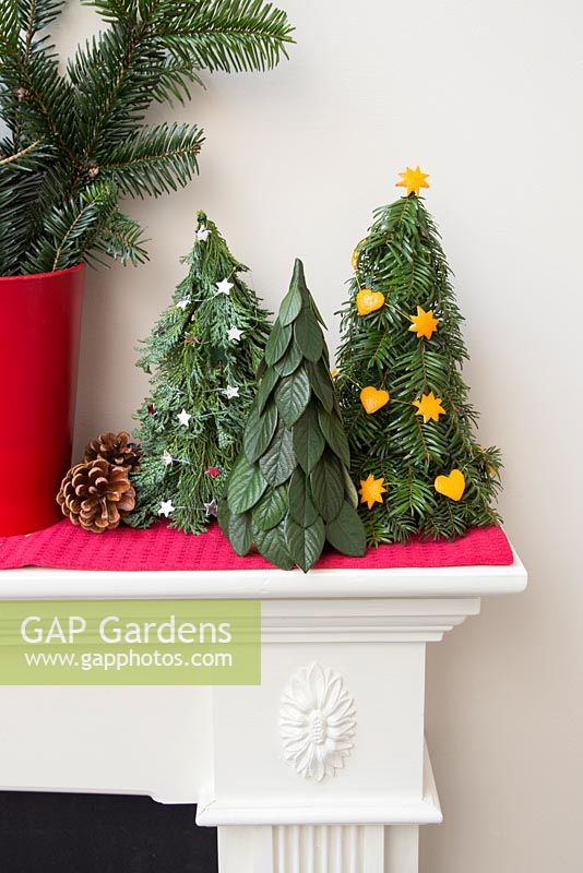 Variety of trees with different decorations on mantelpiece 