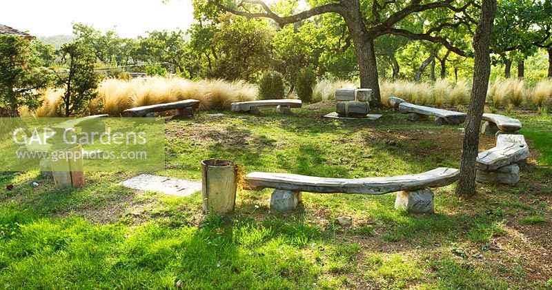 A circle of wooden benches by Marc Nucera in woodland with Stipa tenuissima. Provence, France, Domaine de la Verriere