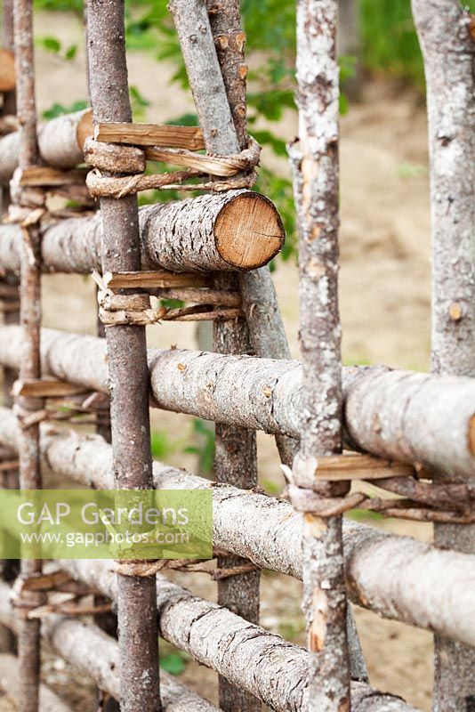 Fence made from tree trunks braided with bark.