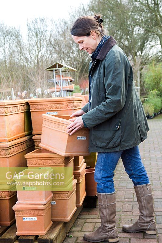 Woman browsing variety of terracotta pots at a garden nursery