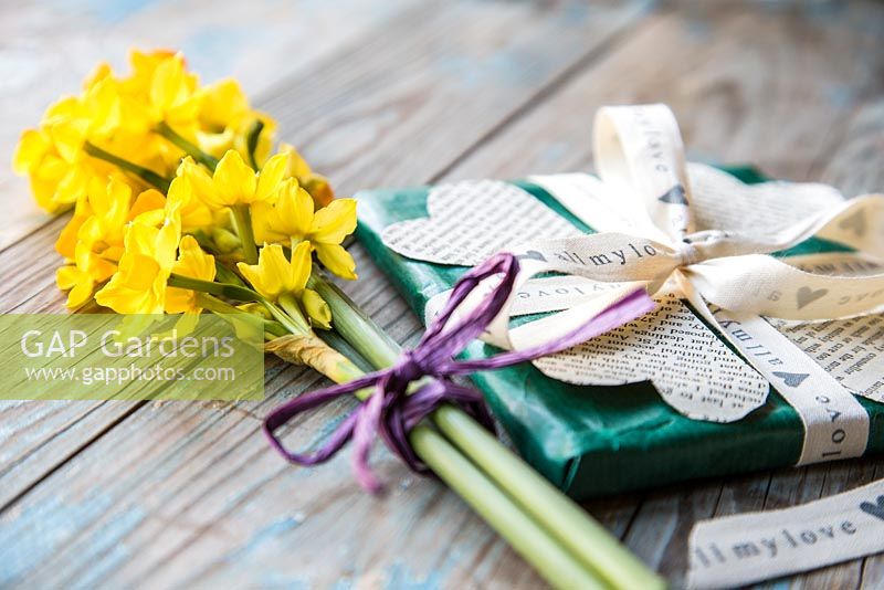 Valentine gift decorated with heart shape cut-outs from a book and a bouquet of Daffodils. Narcissus