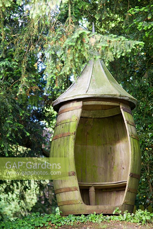 Decorative revolving barrel seat under yew tree - Farleigh House, Hampshire