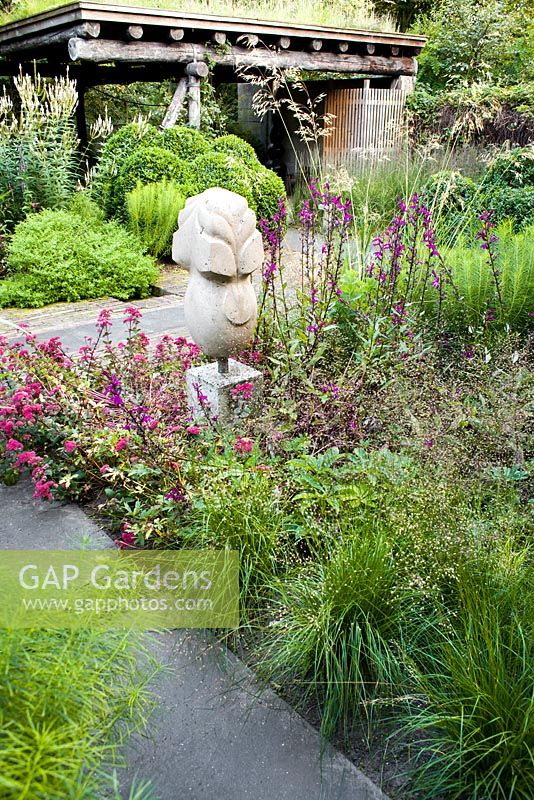 Contemporary garden with statue. Planting includes, Lobelia Tania Asclepias incarnata, Sedum 'Red Cauli'.