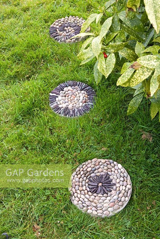 Pebble mosaic paving slabs in grass - stepping stones across lawn 