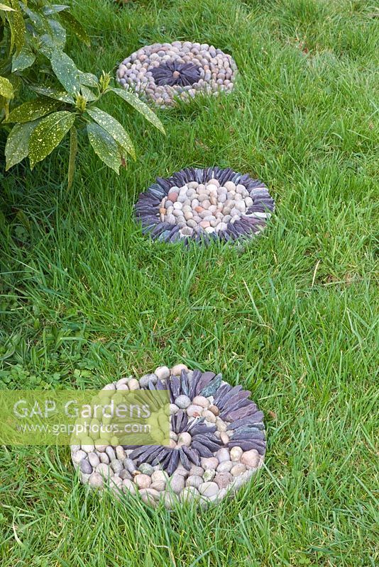 Pebble mosaic paving slabs in grass - stepping stones in lawn 