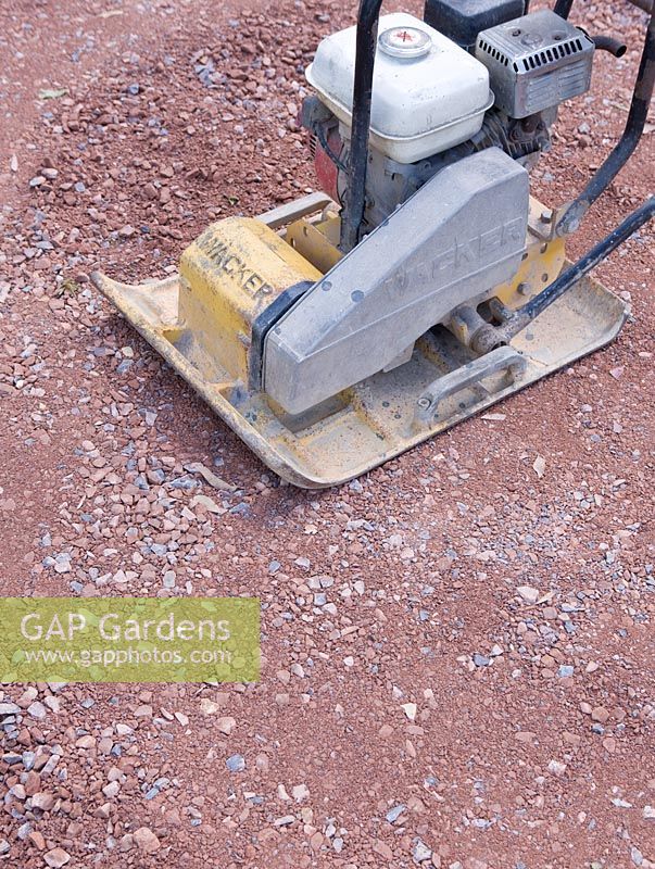 Close up of scalping used beneath paving being compacted with a vibrating plate