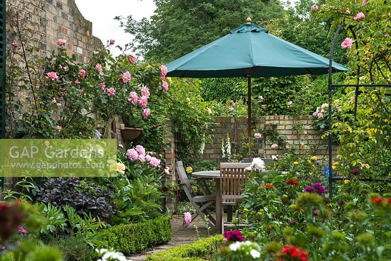 Corner of walled garden with peonies, roses and sweet williams