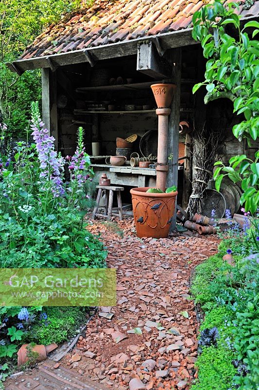 Gravel and crock path leading to potting shed.  Dial A Flight, RHS Chelsea Flower Show 2014. 