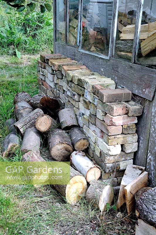 Logs of wood with bricks stacked alongside allotment shed, Golf Course Allotments, London Borough of Haringey