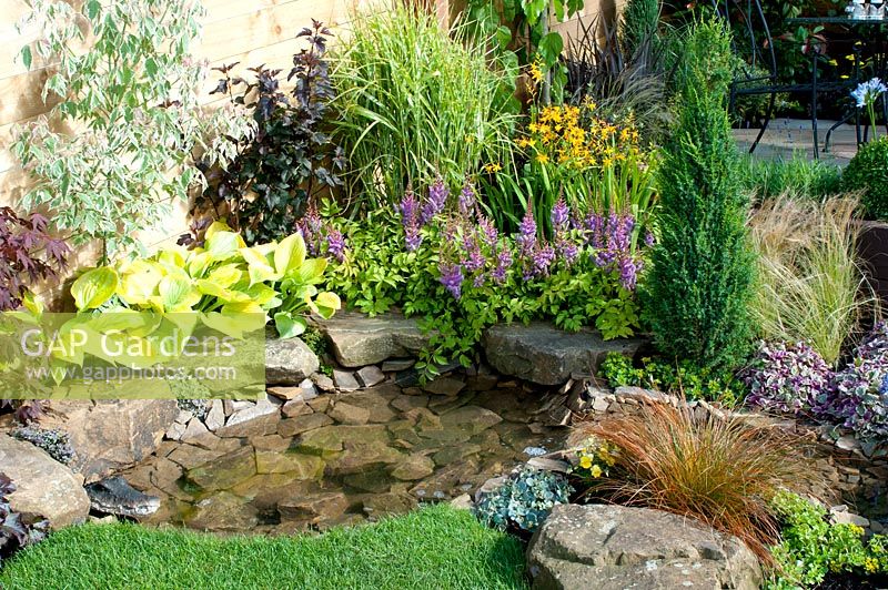 Small garden pool edged by large stones and herbaceous border in the 'Hillside' garden created by Alan Francis Landscapes - Southport Flower Show 2013 