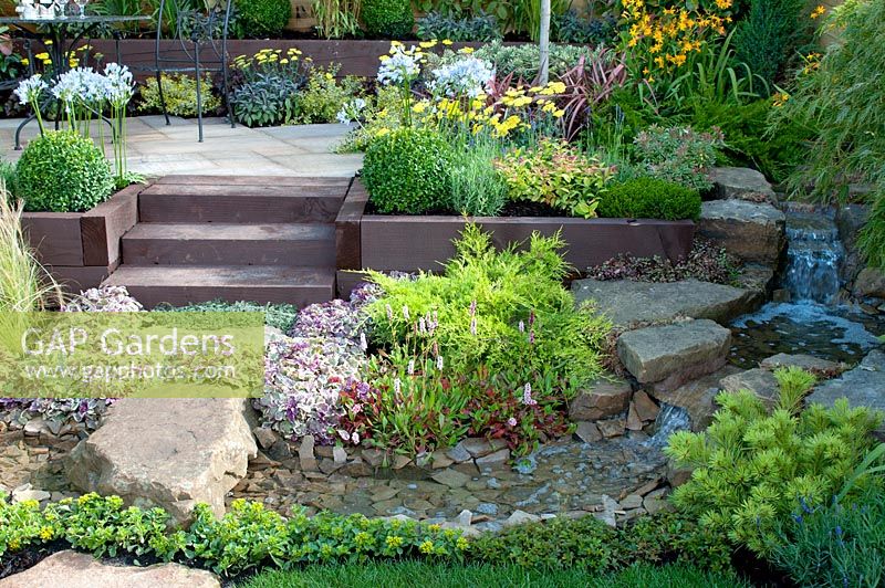 Raised seating area, stream and stepping stone, and colourful beds in the 'Hillside' garden created by Alan Francis Landscapes - Southport Flower Show 2013