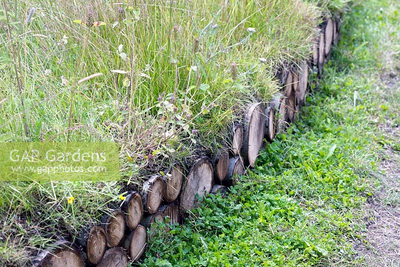Wood trunks as small fence planted with several grasses - Jordans Wildlife Garden. Design: Selina Botham - Silver. Best Show Garden. RHS Hampton court flower show 2014