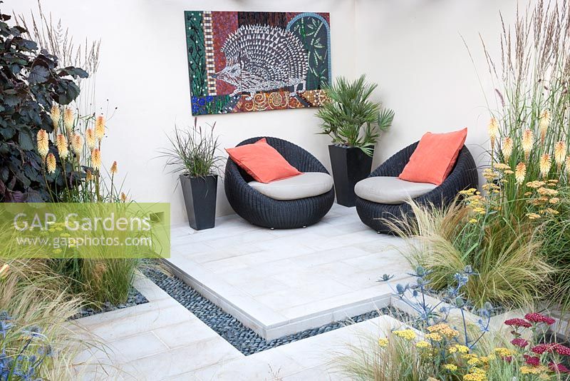 Hedgehog Garden - view of contemporary outdoor living space with planting of grasses, achillea, eryngium and Kniphophia. Designer - Tracy Foster - Sponsor - Peoples Trust for Endangered Species PTES - British Hedgehog Preservation Society BHPS