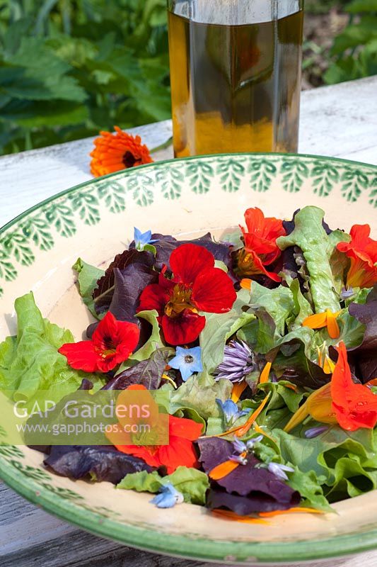 Salad leaves with edible flowers in rustic bowl - nasturiums, borage, chives and calendula