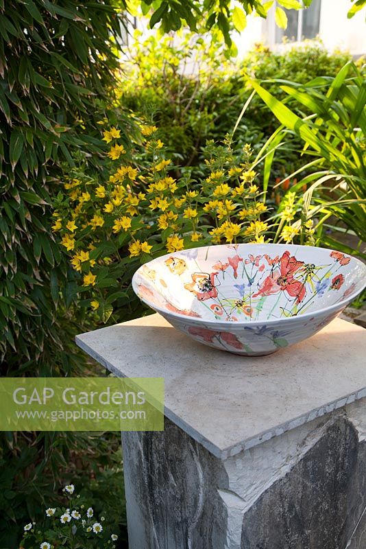 Decorative hand crafted ceramic floral bowl by artist Tina Davies amongst summer planting including Loosestrife