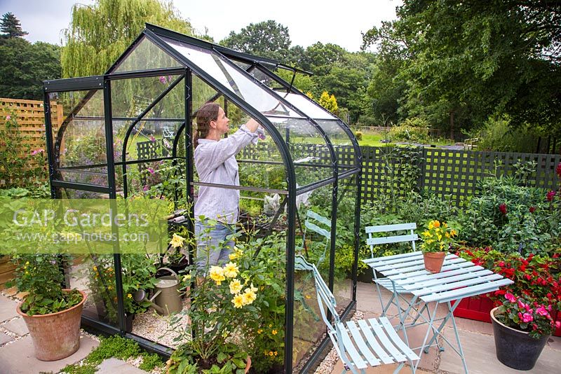 Woman opening the windows of a Greenhouse to allow air flow