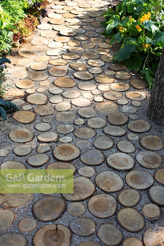 Log pathway leading through vegetable garden. Garden path made from sliced Logs with gravel and sand infill, 