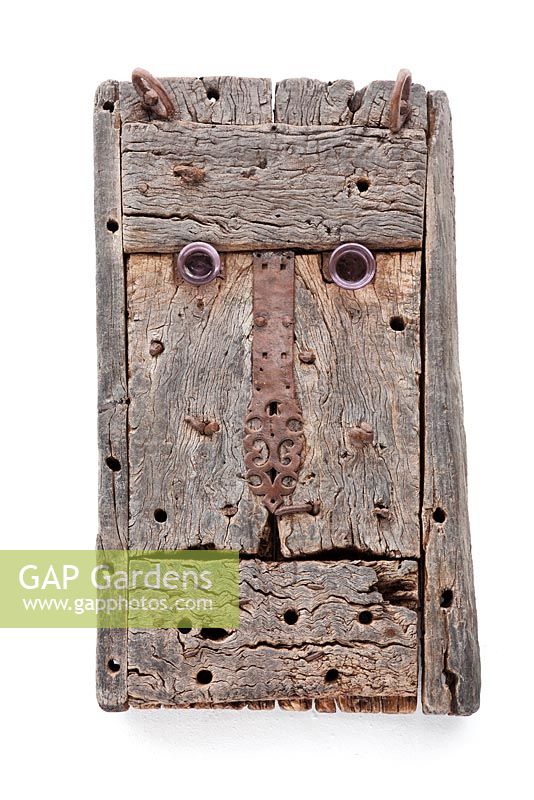 Weathered wood face sculpture on white washed wall 