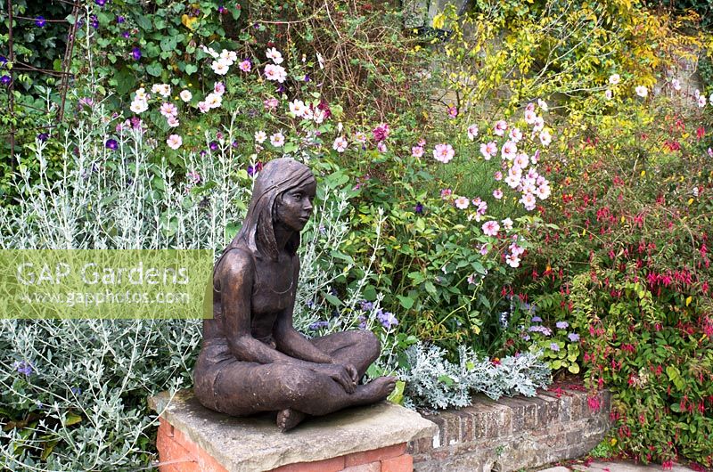 Cosmos 'Sensation Mix' and Fuschia with sculpture in the Pool Garden at Pashley Manor Gardens. September. East Sussex.