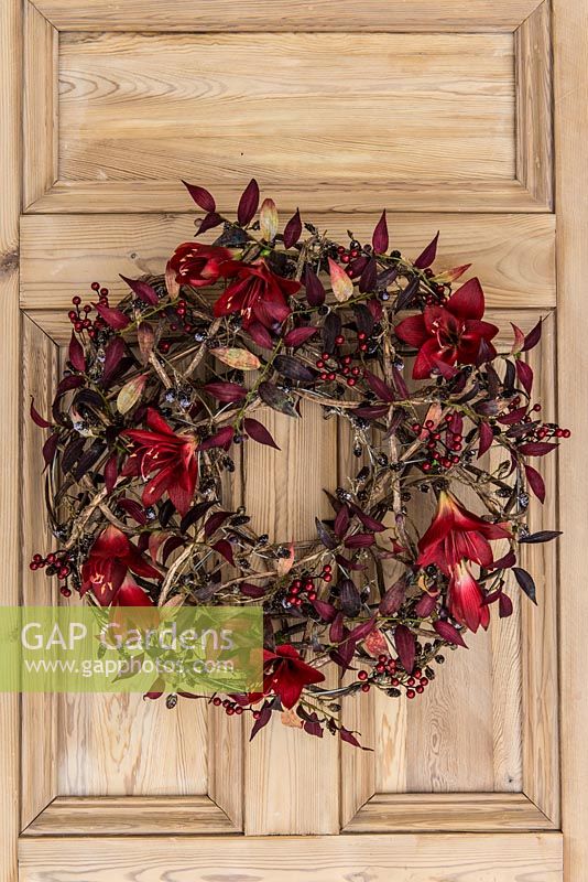 Everlasting Christmas wreath. Silk flowers, foliage and artificial berries are secured onto a circular base of entwined stems.