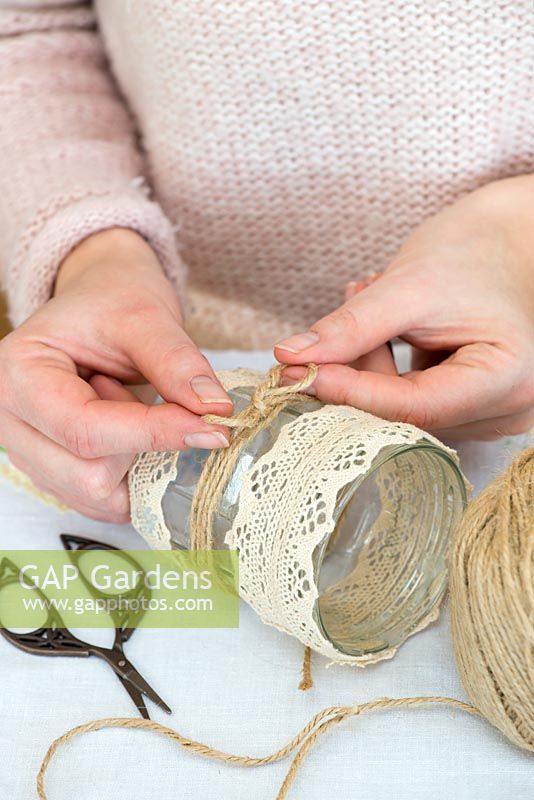 Decorating glass jars for garden posies step by step. Tying a bow from the gardener's jute twine string around a glass jar.