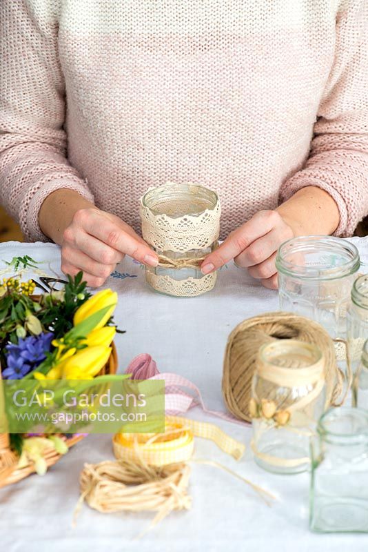 Decorating glass jars for garden posies step by step. Tying a bow of gardener's jute twine string around a glass jar.