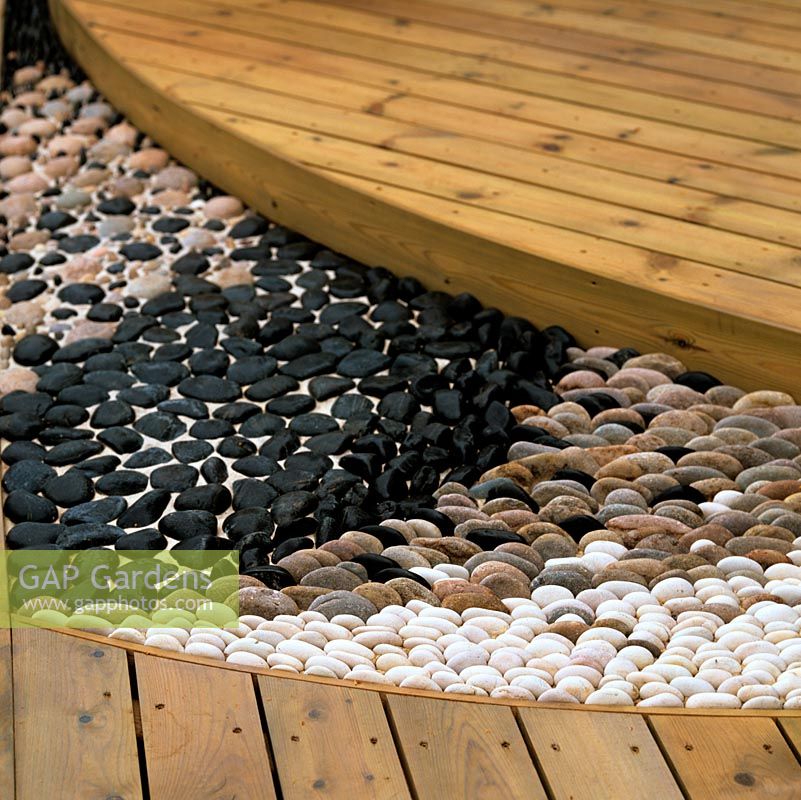 Where a timber deck changes levels, a reflexology path is laid from light and dark coloured pebbles.