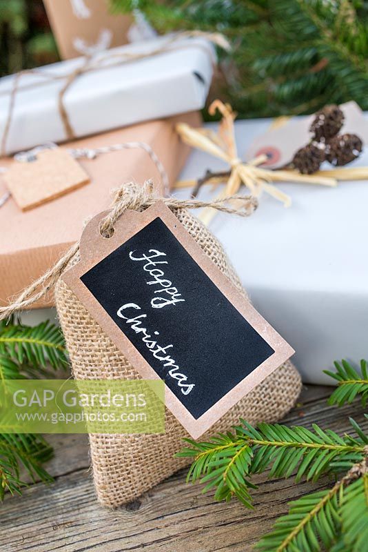 Christmas present wrapped in Hessian, accompanied with Yew foliage. Featuring cork tag and Alder decoration
