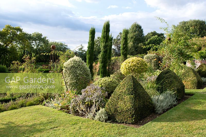 Clipped Buxus topiary, Euonymus fortunei ball, Italian cypress - Cupressus sempervirens with rusted obelisk designed and manufactured by Jane Howard of 'Room in the Garden' on the Cowdray estate.