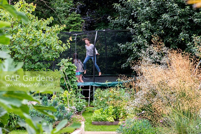 Lily, 10, and Scarlett, 13, play on the trampoline tucked away at the bottom of the garden.