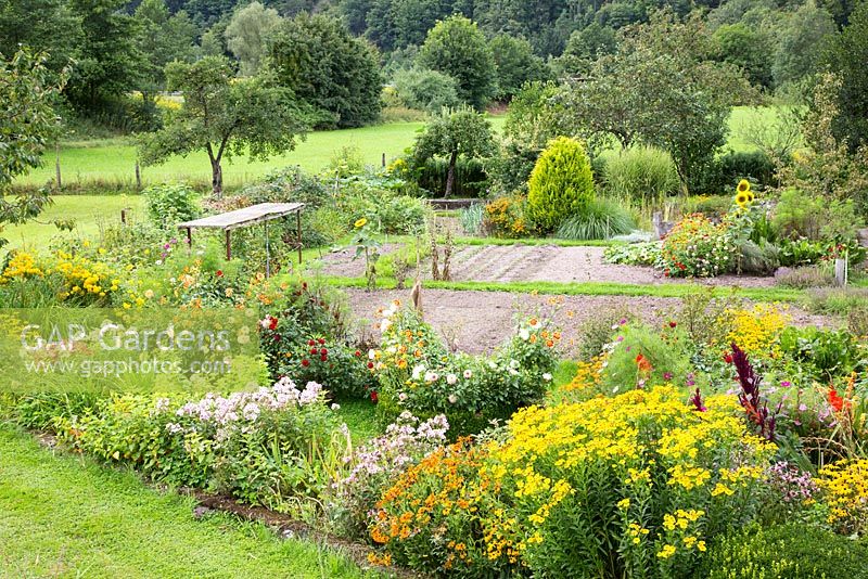 Embedded in a landscape with fruit trees, meadows and a forest, a rural garden plot with perennial borders
