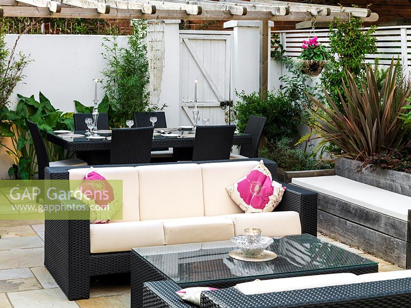 Outdoor room with sofas, dining table, gas effect fire, built-in seating, mirror, steel panel water feature, lighting, raised beds.