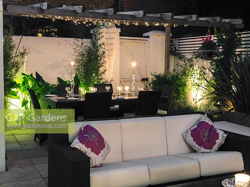 Outdoor room at night with sofas, dining table and lighting