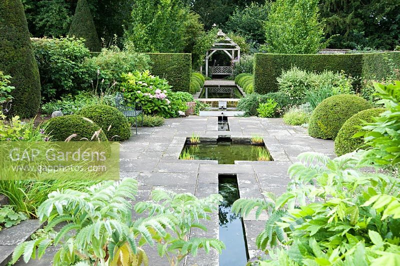 The Rill Garden planted in cool greens, with clipped yew, hydrangeas and Melianthus major. Wollerton Old Hall, nr Market Drayton, Shropshire, UK