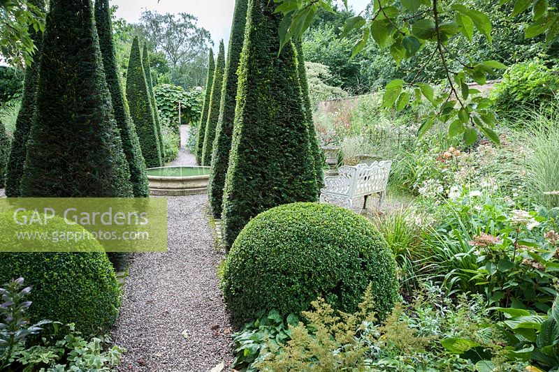 The Well Garden with central reflecting pool, tall yew spires and clipped box. Wollerton Old Hall, nr Market Drayton, Shropshire, UK