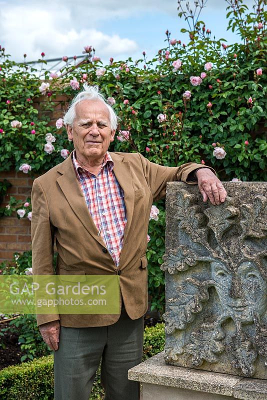 Portrait of Mr David Austin OBE VMH, beside a sculpture of The Green Man, by his late wife, Mrs Pat Austin, a talented sculptor.