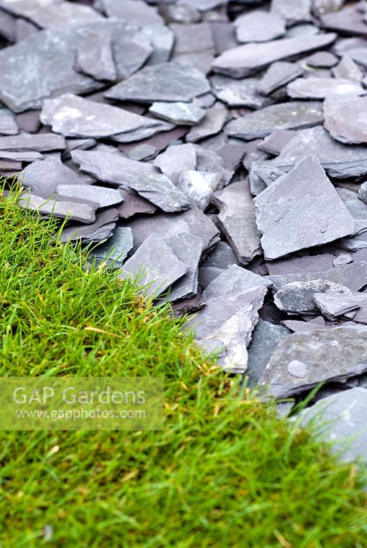 Slate stone chippings used for path or mulch against grass lawn.