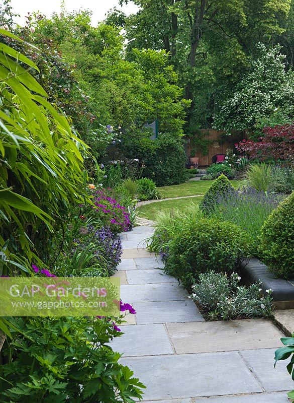 A natural flagstone path leads along a mixed flower border through to the lawn.