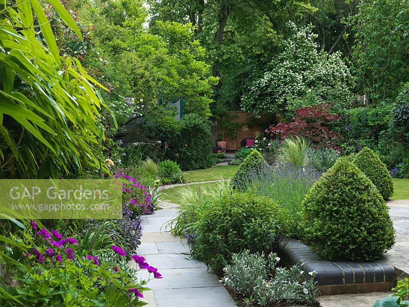 A natural flagstone path leads along a mixed border and topiary through to the lawn.
