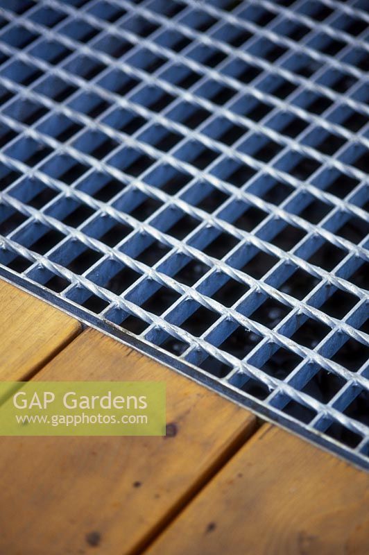 Detail of galvanised metal grill and wooden decking