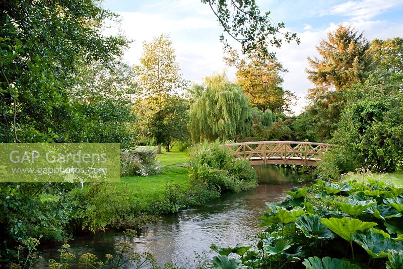 Wooden bridge across stream in country garden.