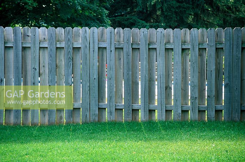 Wooden pallisade fence fronted by lawn. Milford, Michigan, USA