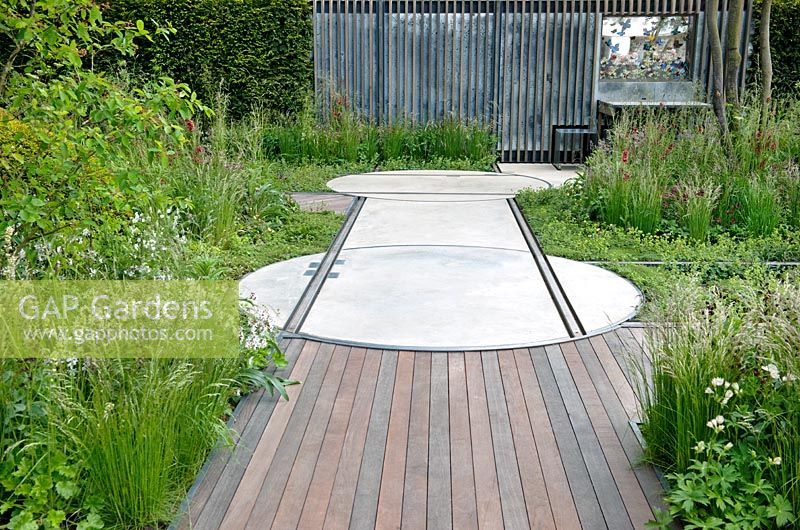 Decking, rails for moveable shack, wall and mixed herbaceous borders of grasses and flowers. The Cloudy Bay and Bord na Mona garden, Chelsea Flower Show 2015

