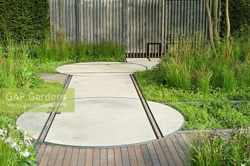 Rails embedded in pathway and rotating discs to carry moveable 'shack'. The Cloudy Bay and Bord na Mona garden, Chelsea Flower Show 2015


